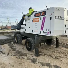 Maszyna do betonu Dromaxx S-22EZ pracuje na budowie. Obok świeżego betonu widać zbrojenie pod słup.