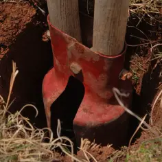 Narzędzie do kopania dołków pod słupki ogrodzeniowe. Pokazuje, jak ustawić słupki ogrodzeniowe na nierównym terenie, zagłębiając je w ziemi.
