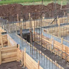 Szalowanie ław fundamentowych zbrojonych stalowymi prętami, gotowe do zalania betonem.