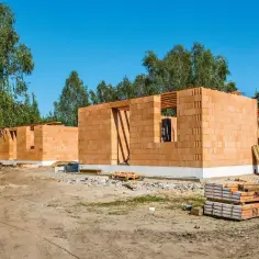 Budowa domu murowanego z pustaków ceramicznych. Widać fundamenty i wznoszone ściany.
