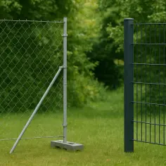 Tymczasowe ogrodzenie budowlane z siatki i paneli, oddzielające teren zielony.