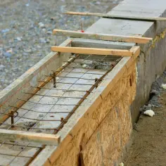Gotowe zbrojenie na fundamenty, z siatką stalową i drewnianą szalunką, czeka na zalanie betonem.
