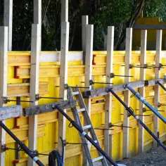 Szalunek co to? Żółte płyty i drewniane słupy tworzą konstrukcję do wylewania betonu.