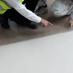 Dwóch pracowników ocenia nową posadzkę przemysłową w garażu. Jedna osoba wskazuje na gładką, jasną powierzchnię.