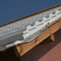 Ocieplenie dachu styropianem w trakcie budowy. Białe płyty styropianowe układane są na drewnianej konstrukcji dachu, pod folią dachową.