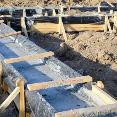 Budowa domu: ławy fundamentowe krok po kroku. Betonowe koryta w drewnianych szalunkach, gotowe do dalszych prac.