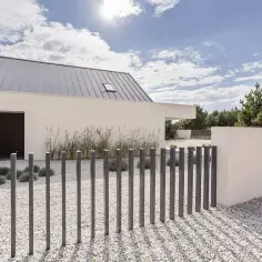 Nowoczesny dom z betonowym ogrodzeniem. Jak zrobić ogrodzenie z betonu architektonicznego? Proste słupki i białe kamienie.