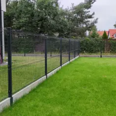 Ogrodzenie panelowe z podmurówką betonową na tle domu i zielonego trawnika.