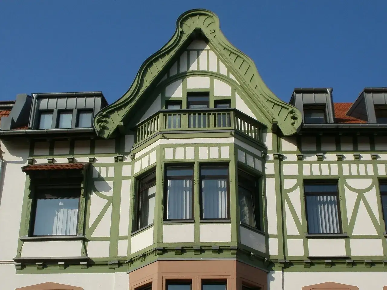 Elegancki ryzalit z zielonymi zdobieniami i balkonem, część fasady secesyjnej kamienicy.