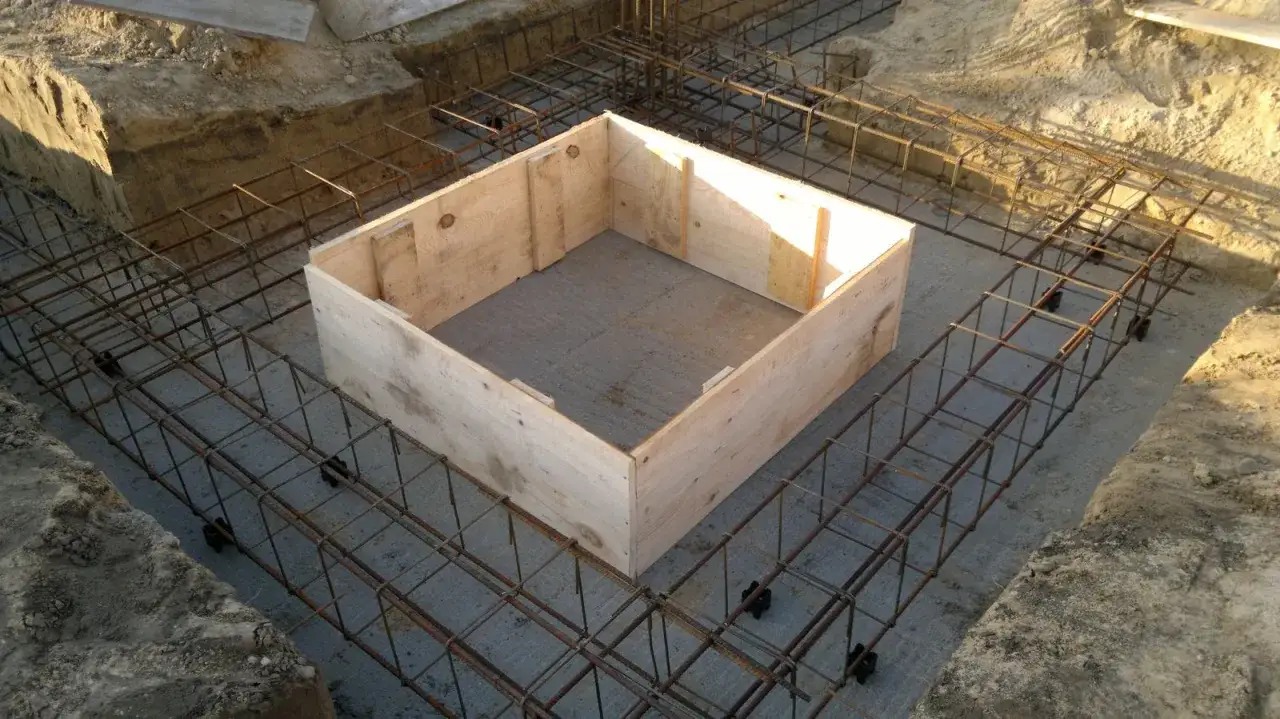 Budowa ław fundamentowych krok po kroku: szalunek drewniany i zbrojenie stalowe czekają na beton.