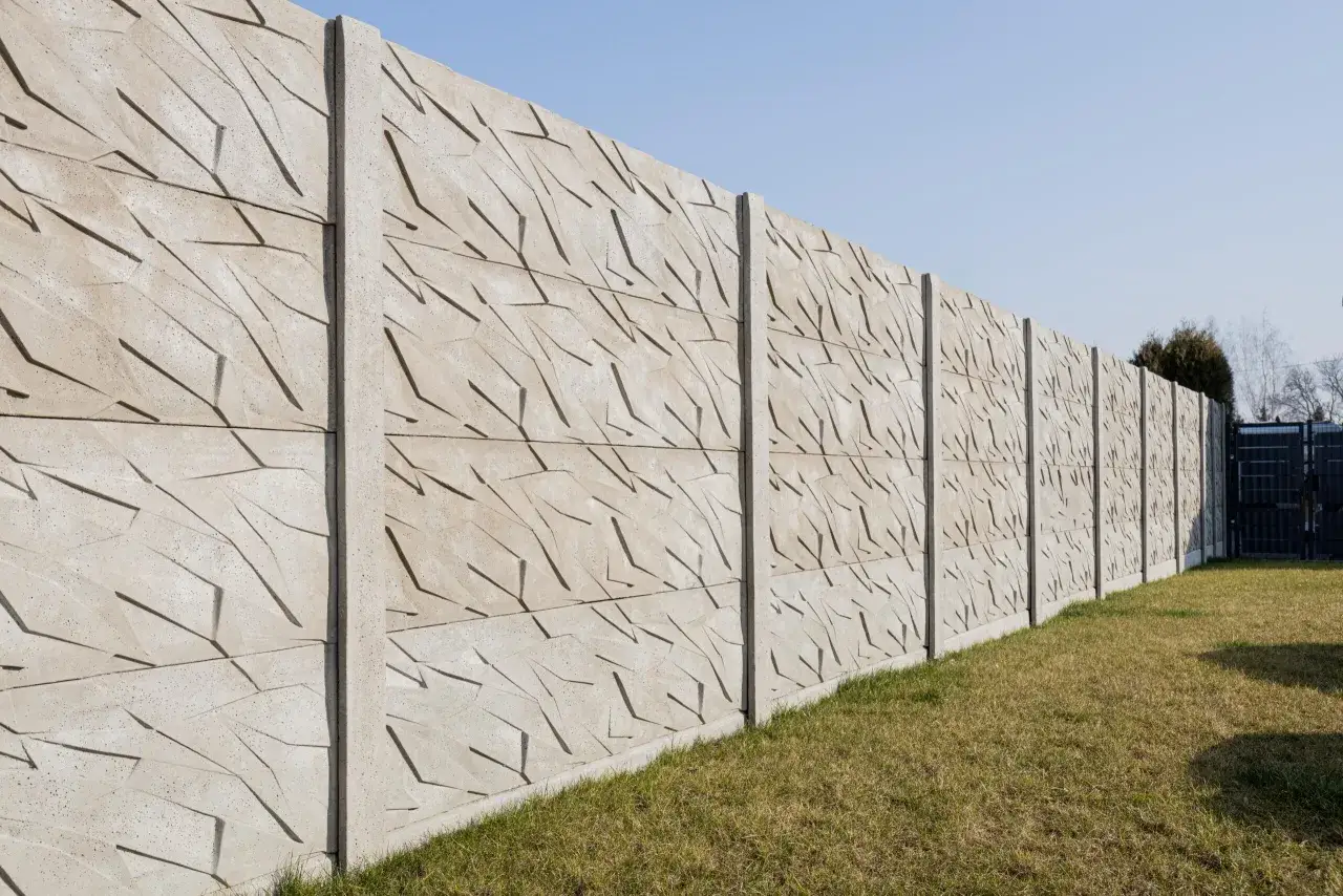 Betonowe przęsła ogrodzenia z geometrycznym wzorem, idealne do zastosowania, jak ustawić słupki ogrodzeniowe na nierównym terenie.