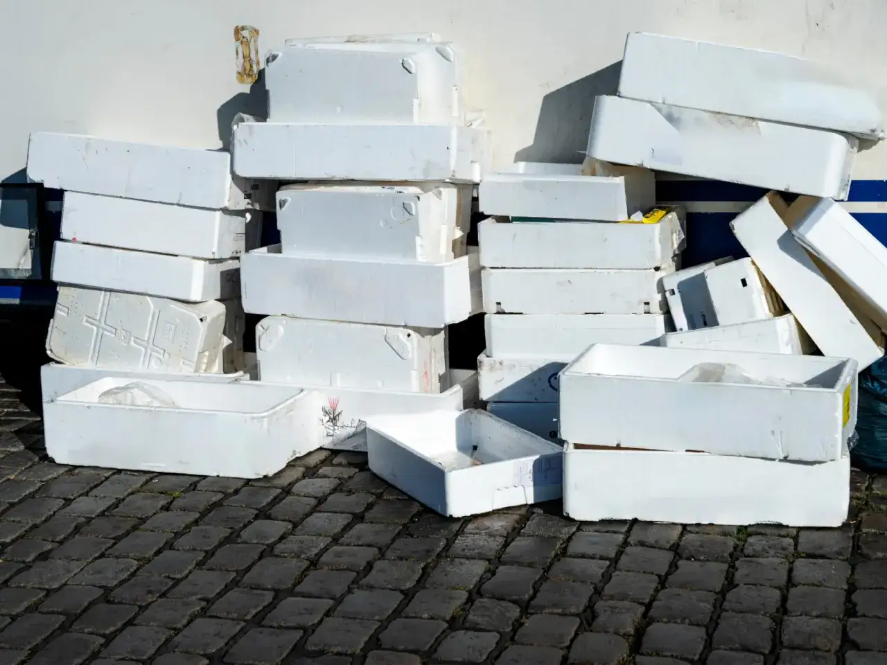 Stosy białych pojemników ze styropianu, które mogą być rozpuszczane przez niektóre rozpuszczalniki, leżą na bruku.