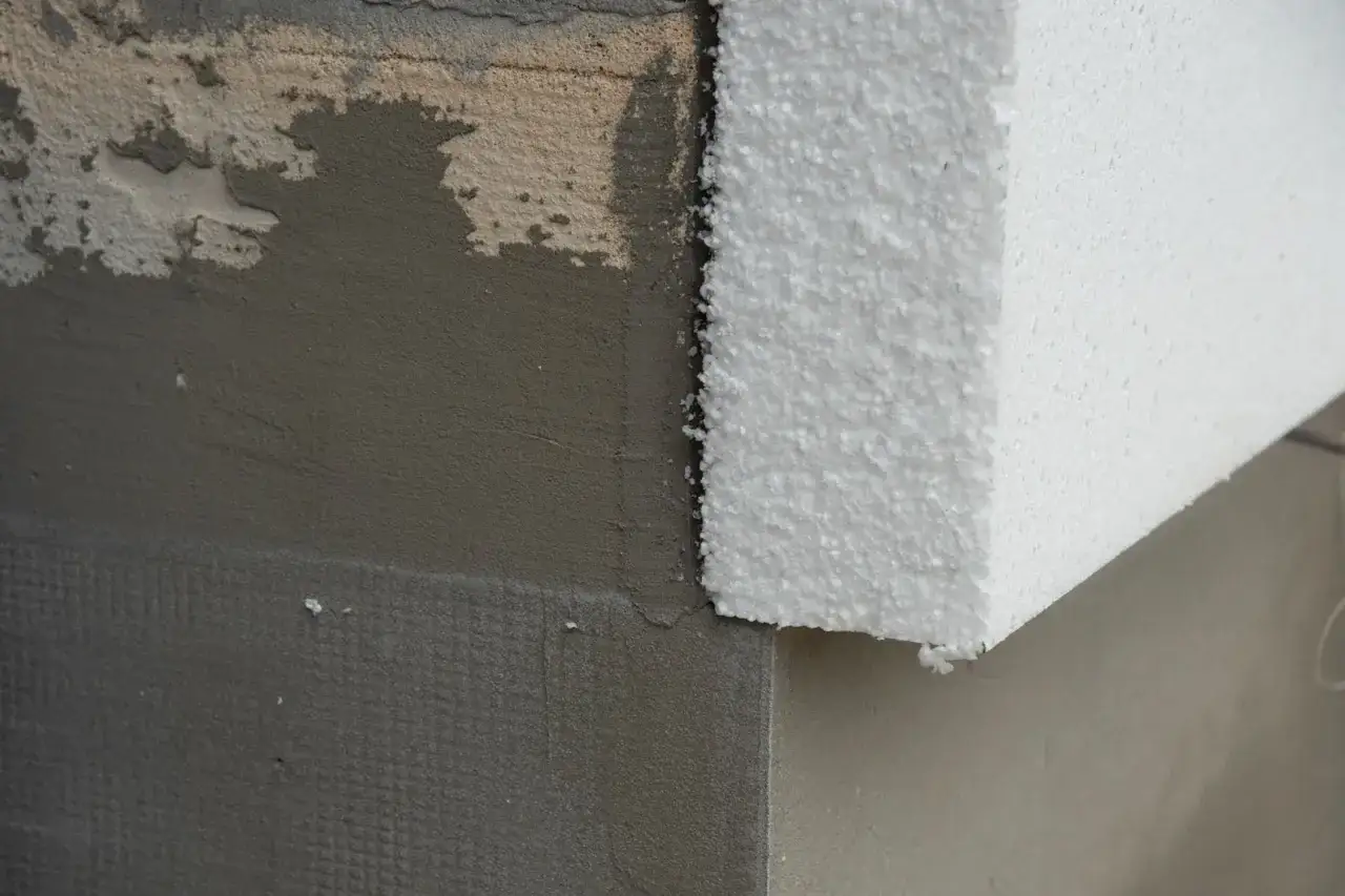 Fragment ocieplenia budynku: szary tynk z siatką i biały styropian. Czy to styrobeton czy styropian?
