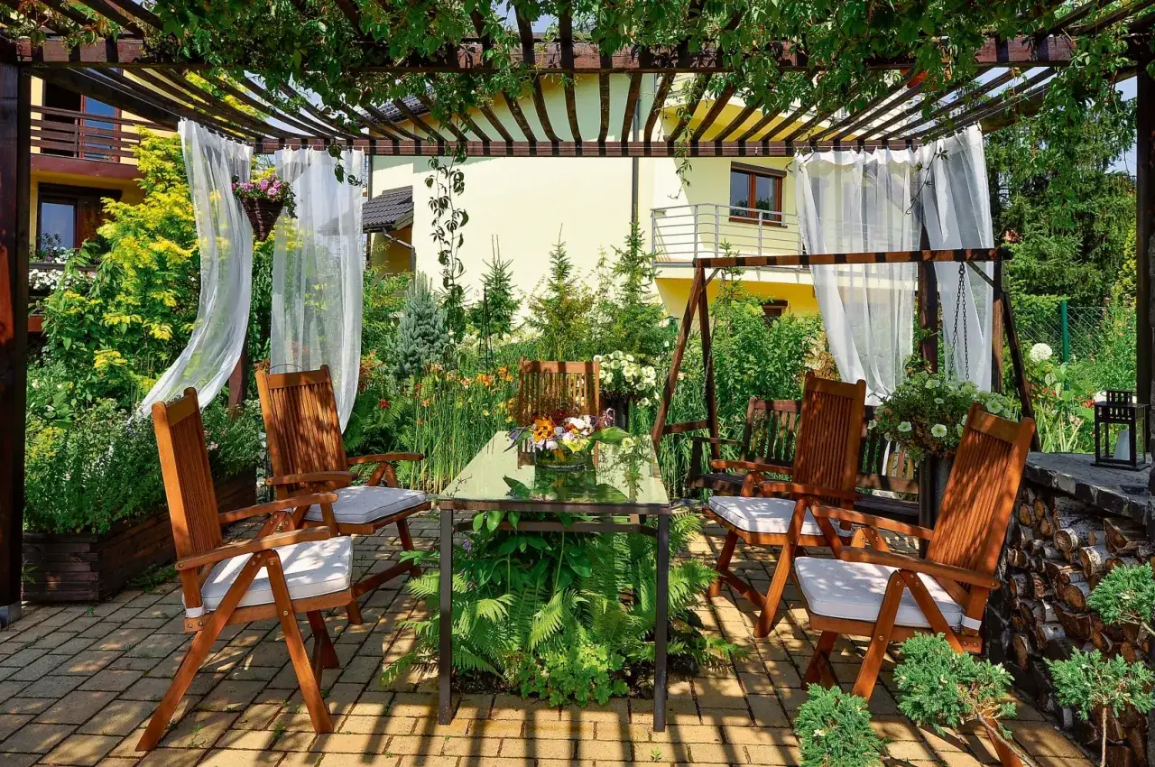 Zasłony i roślinność tworzą przytulną atmosferę, idealną do relaksu. To świetny pomysł, czym ogrodzić taras, by stworzyć prywatną oazę.